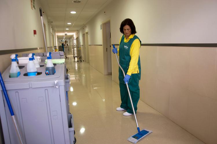 Empleada de Brócoli limpiando el suelo del pasillo de un hospital